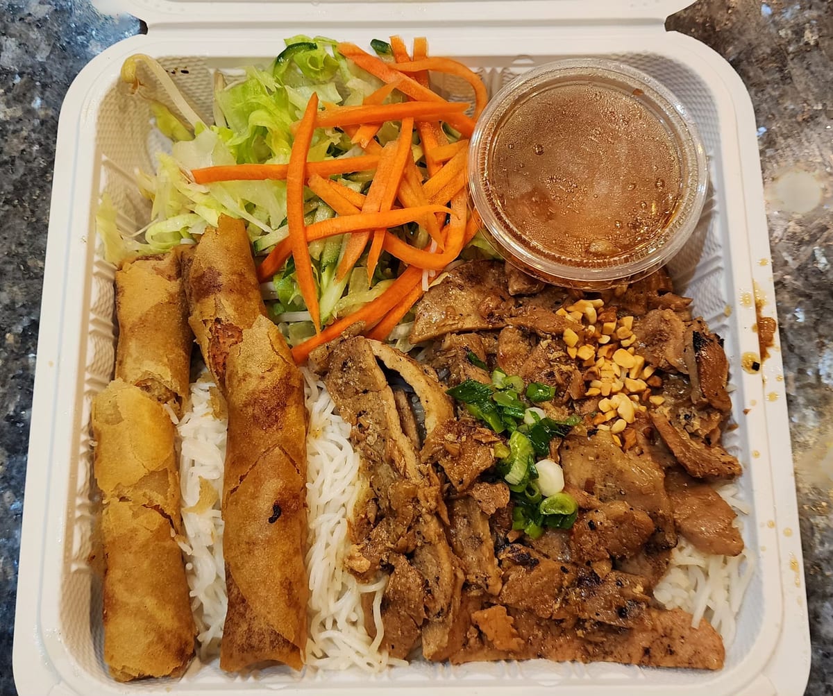 A take-out vermicelli bowl with grilled pork, spring rolls, pickled carrot, peanuts and dipping sauce